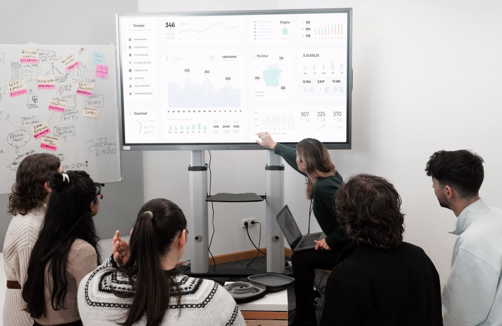 A group of professionals comparing data and charts on a large screen during a technology evaluation meeting