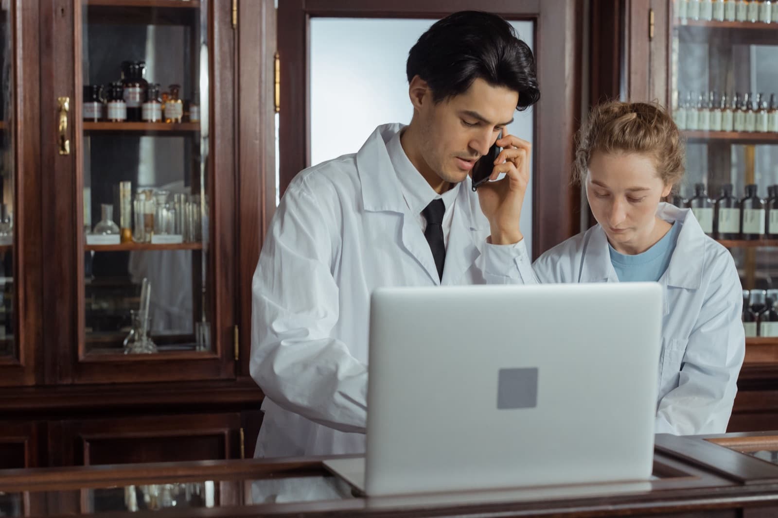 Two pharmacists at a laptop reviewing prior authorization software together in a pharmacy