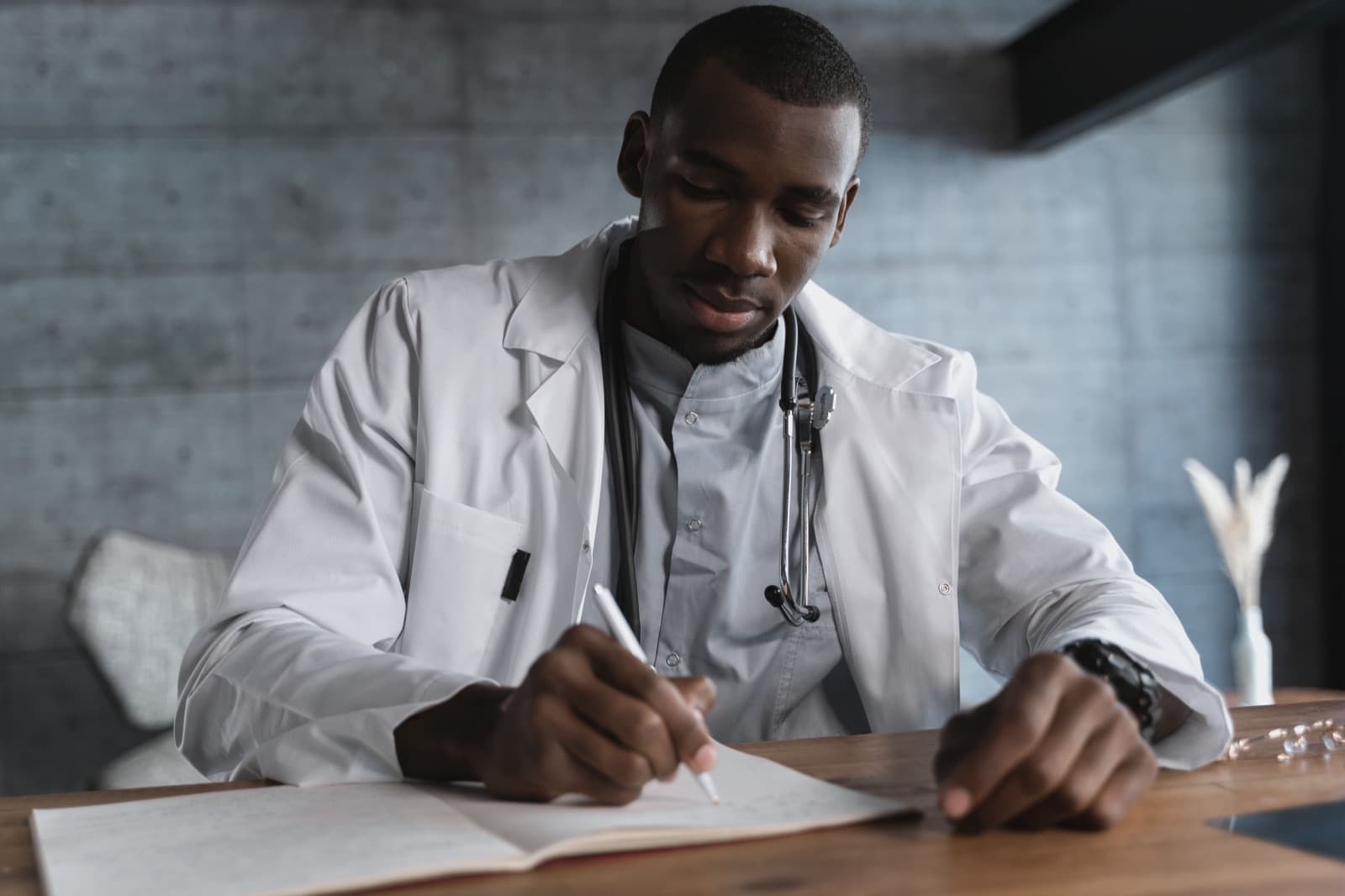 A clinician in a white coat writing a supporting statement at a desk