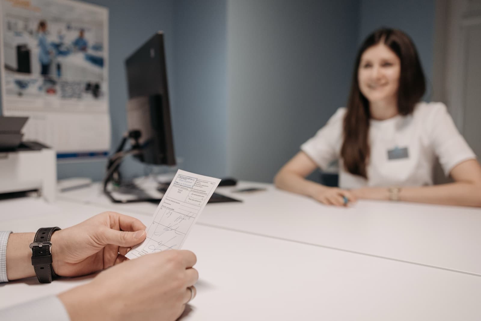 A prescriber reviewing a signed prescription slip across a desk before submitting it for prior authorization